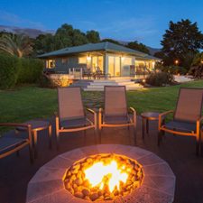 outdoor fire pit in a backyard surrounded by chairs