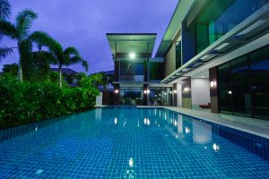 a beautiful modern home with a rectangular pool at night