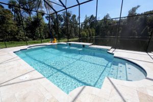 Swimming pool in a covered gated space, surrounded by patterned concrete. 