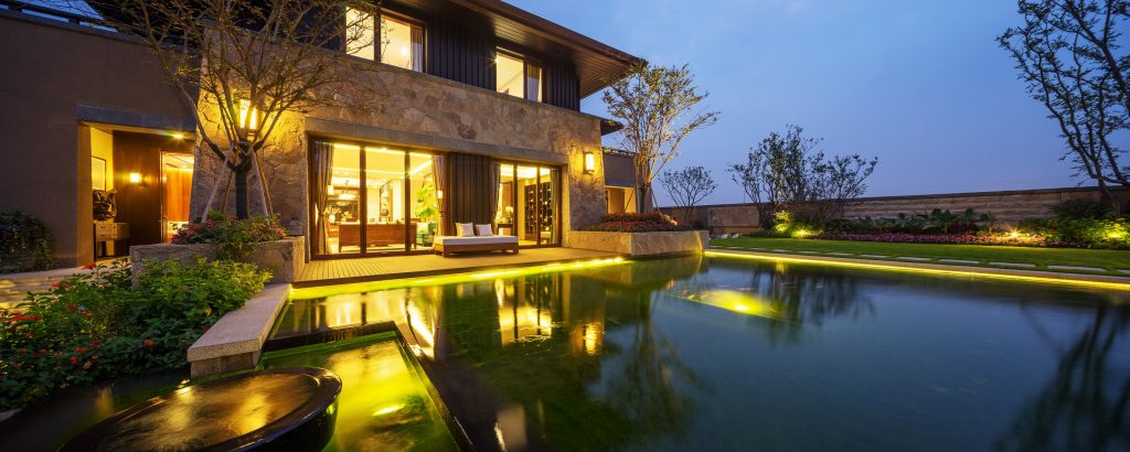 a backyard with ponds and a large pool at dusk