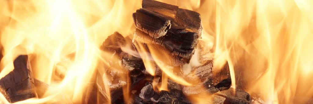 a close up of an outdoor fire pit with flames currently roaring